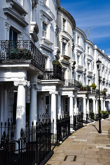 A row of white Georgian-style terraced houses along Gloucester Terrace in Paddington, featuring ornate architectural details, black wrought iron balconies, and large sash windows. The pavement in front is clean and well-maintained, with black metal railings and street lamps visible, under a clear blue sky. This setting illustrates the type of residential properties that Paddington Carpet Cleaners services for thorough surface cleaning, deep cleaning, and sanitisation of domestic environments within the W2 postcode area.